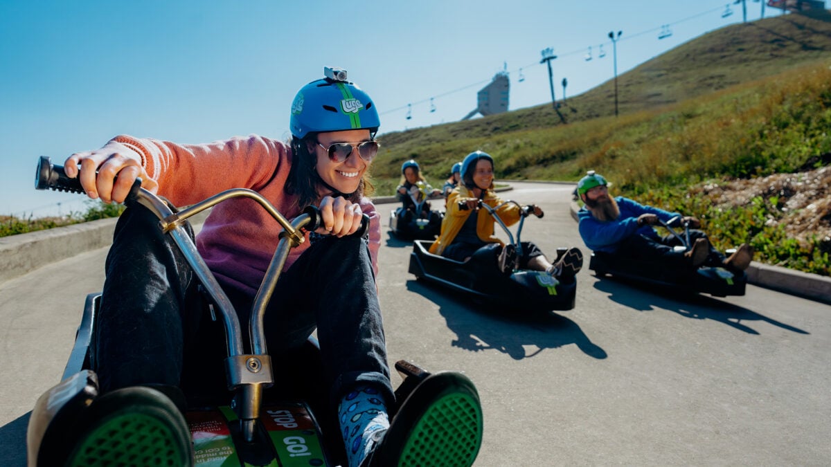 People smile as they ride around a corner at Downhill Karting Calgary.
