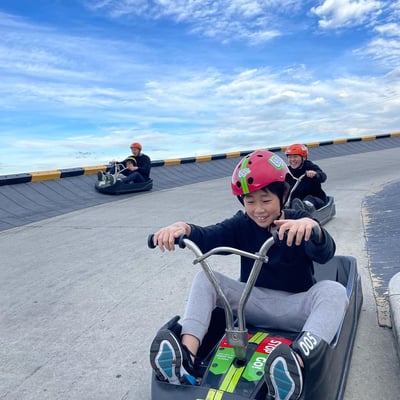 A group of kids and adults race down the tracks at Downhill Karting Calgary.
