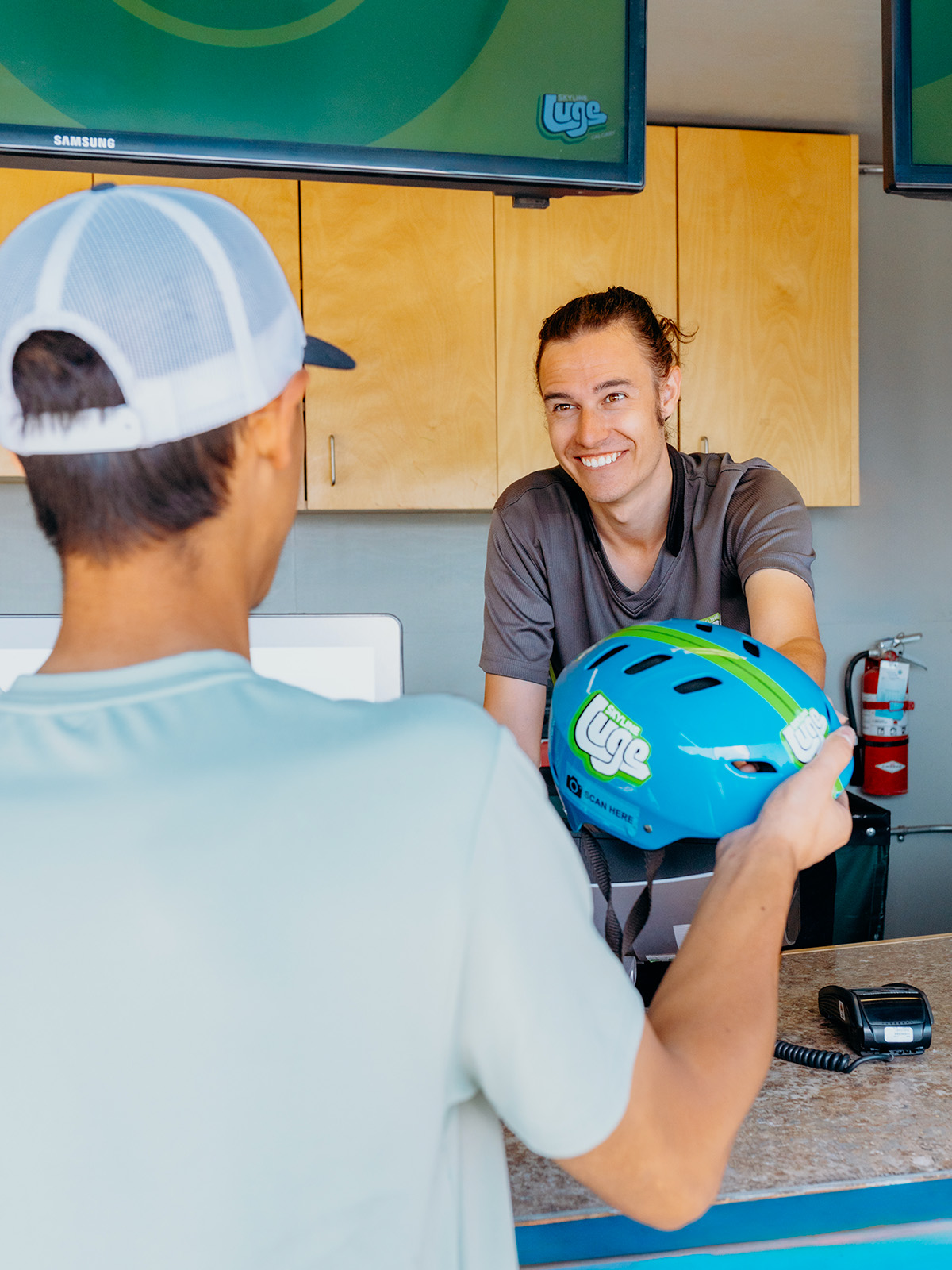 An employee interacts with a Downhill Karting Calgary customer at the ticketing kiosk.