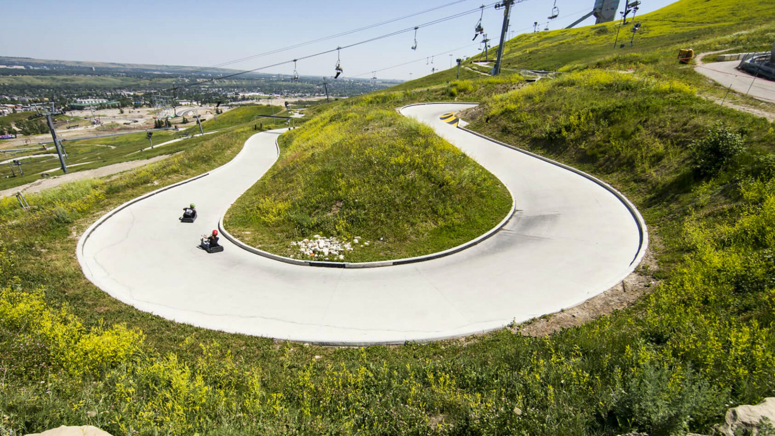 A panoramic photo of guest riding round a large horseshoe corner at Downhill Karting Calgary.