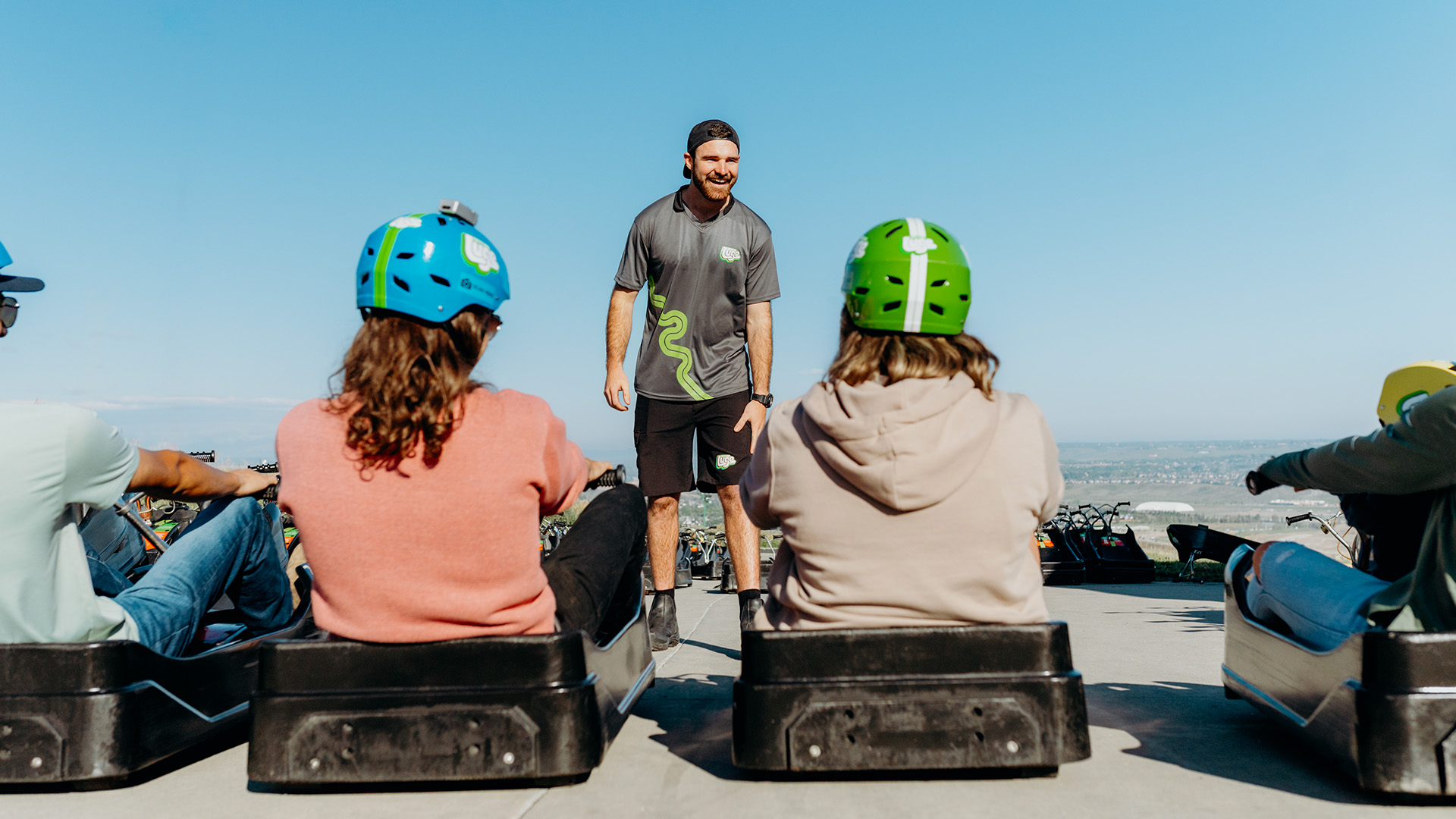 A Downhill Karting Calgary employee smiles as he shows guests how to ride their karts correctly.