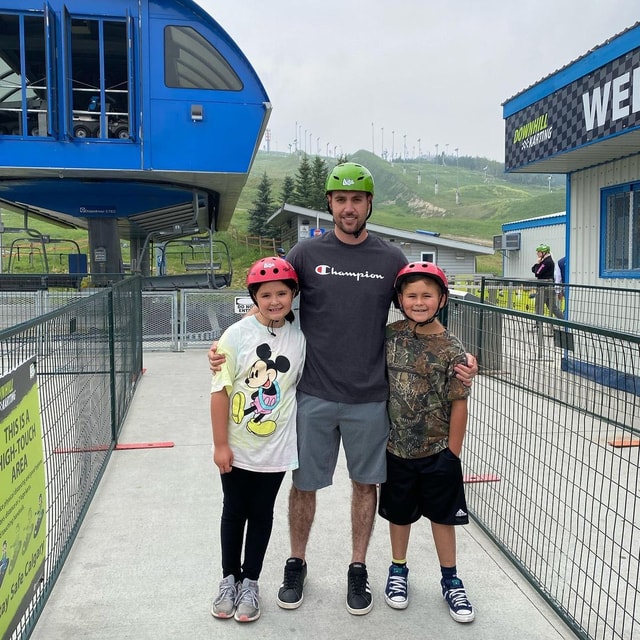 A father hugs his two kids and poses for a photo at Downhill Karting Calgary.