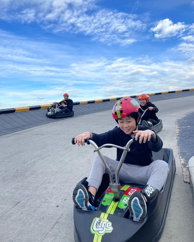 A group of kids and adults race down the tracks at Downhill Karting Calgary.
